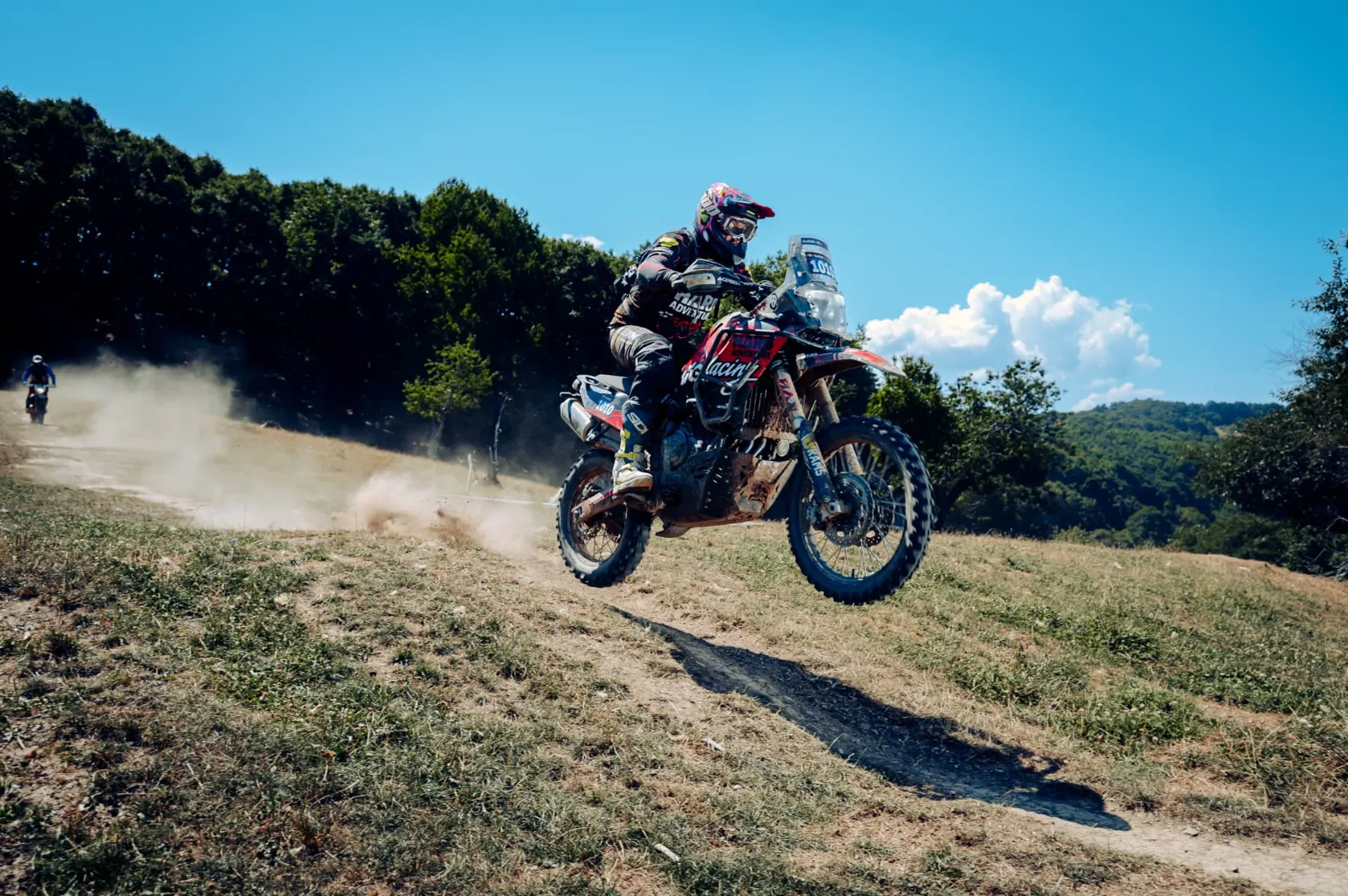 Rider airborne over a dusty dirt crest